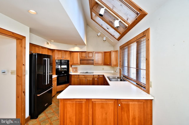 kitchen with light floors, a peninsula, a sink, black appliances, and light countertops