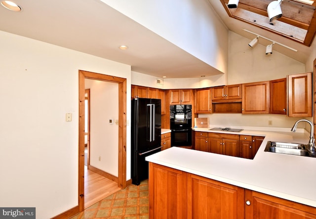 kitchen with black appliances, a sink, a peninsula, light countertops, and light floors