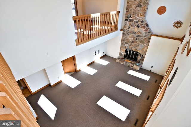 living area featuring a fireplace, baseboards, a towering ceiling, and carpet floors