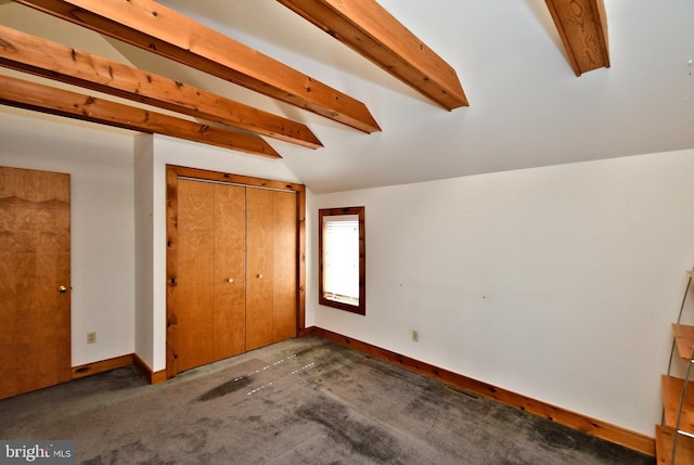 unfurnished bedroom with a closet, baseboards, and vaulted ceiling with beams