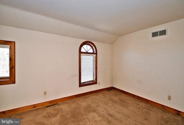 unfurnished room with vaulted ceiling, visible vents, baseboards, and carpet floors