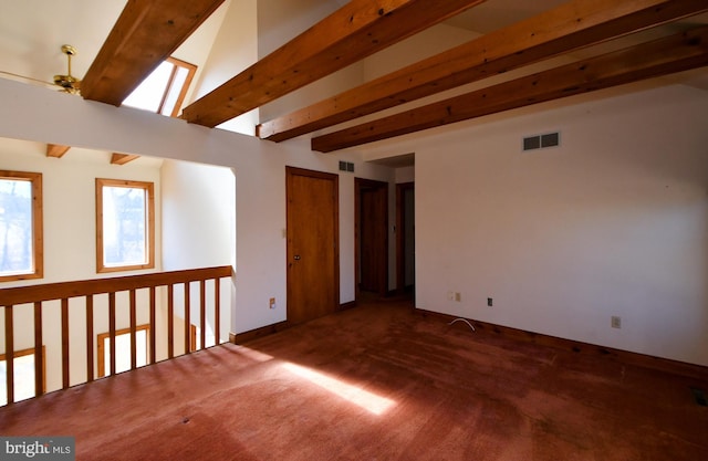 carpeted spare room with beamed ceiling, baseboards, visible vents, and ceiling fan