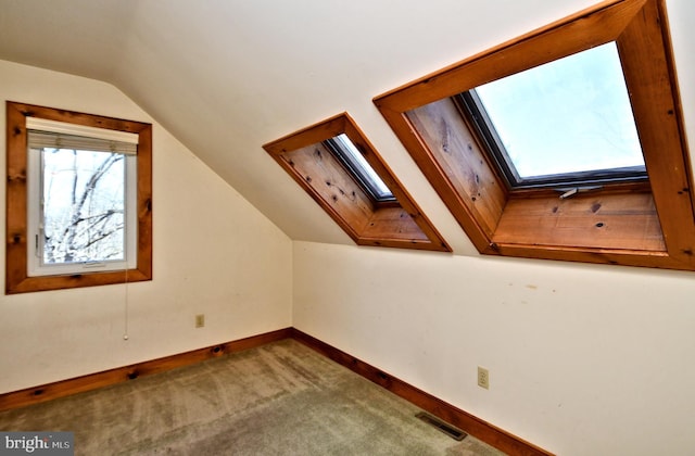 bonus room with visible vents, vaulted ceiling with skylight, baseboards, and carpet flooring