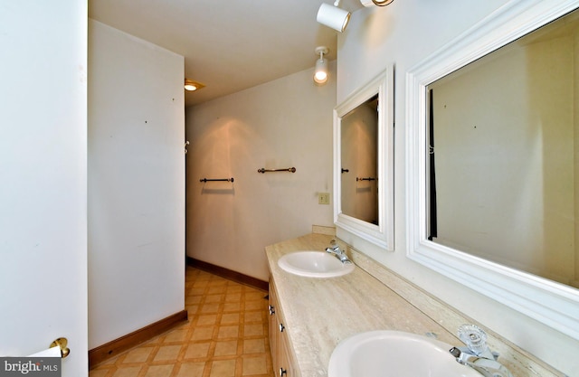 bathroom with a sink, baseboards, double vanity, and tile patterned floors