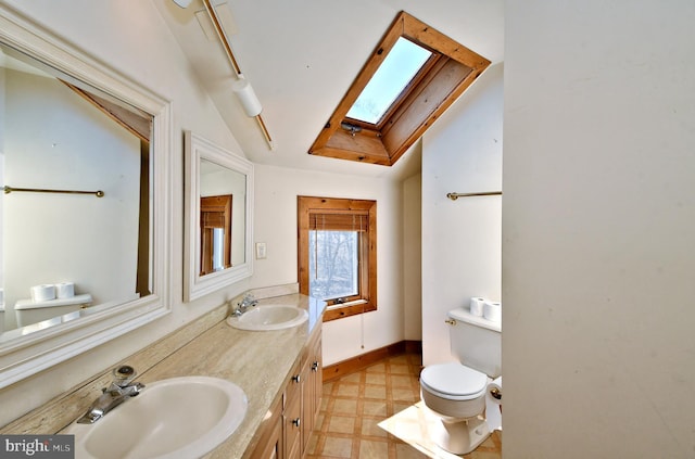 full bathroom with tile patterned floors, vaulted ceiling with skylight, toilet, and a sink