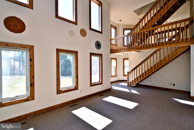 unfurnished living room with stairs, carpet flooring, baseboards, and visible vents