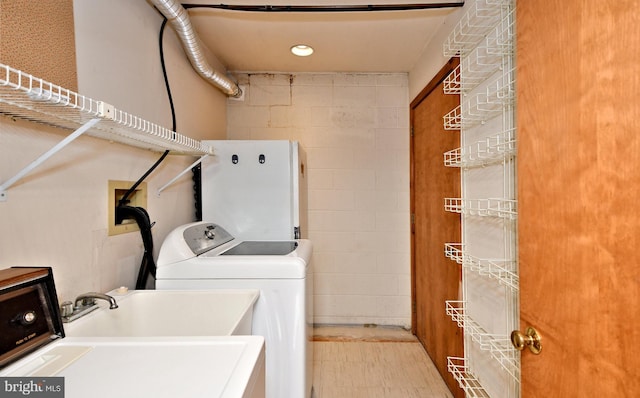 washroom with a sink, laundry area, concrete block wall, and washer and clothes dryer