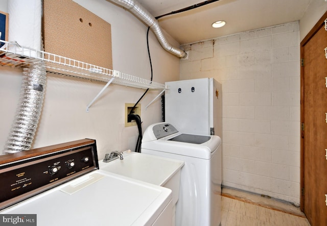 clothes washing area with concrete block wall, laundry area, and washer and clothes dryer