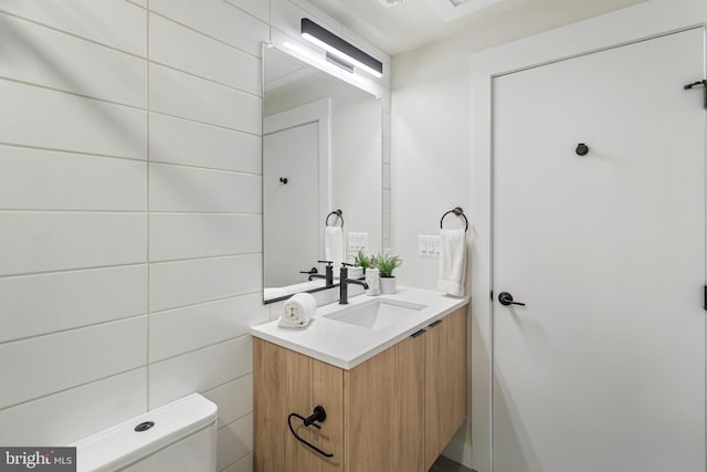 bathroom featuring toilet, tile walls, and vanity