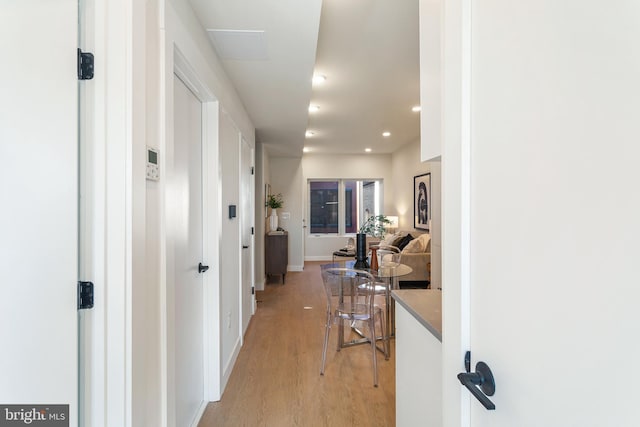 hallway featuring recessed lighting, baseboards, and light wood-style flooring