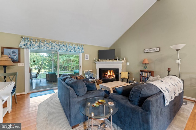 living area featuring a glass covered fireplace, baseboards, and wood finished floors