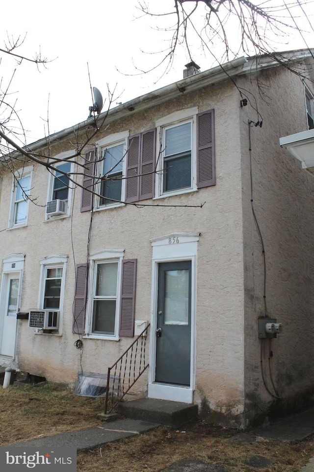 view of front of property featuring stucco siding, cooling unit, and entry steps