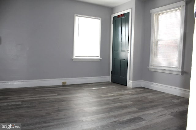 unfurnished bedroom featuring multiple windows, wood finished floors, and baseboards