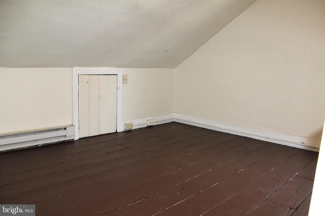 additional living space featuring dark wood-type flooring, baseboard heating, and vaulted ceiling