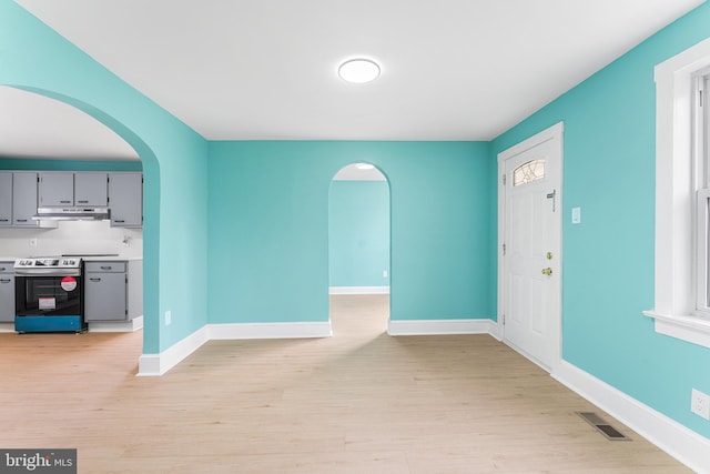 entrance foyer with visible vents, arched walkways, light wood finished floors, and baseboards