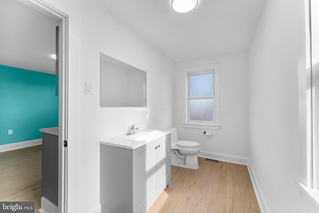 half bath featuring visible vents, toilet, baseboards, and wood finished floors