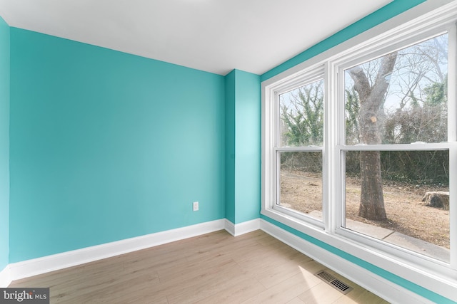 empty room with visible vents, baseboards, and wood finished floors