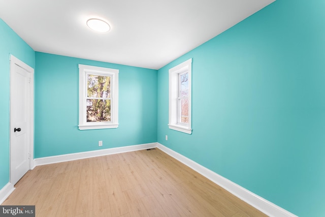 empty room featuring baseboards and light wood finished floors