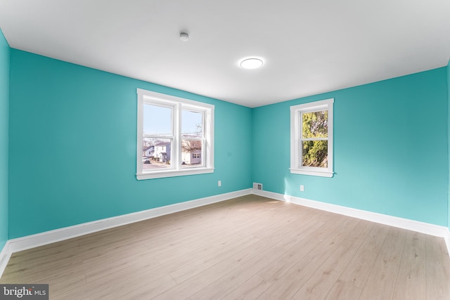 spare room featuring visible vents, baseboards, and wood finished floors