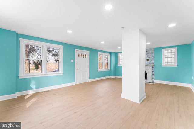 unfurnished living room with visible vents, baseboards, light wood-type flooring, a stone fireplace, and recessed lighting