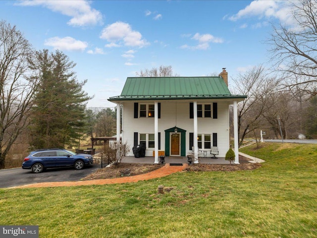 neoclassical home with a standing seam roof, a porch, a chimney, a front lawn, and metal roof