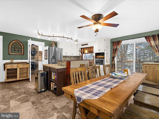 dining area with stacked washer / drying machine and a ceiling fan