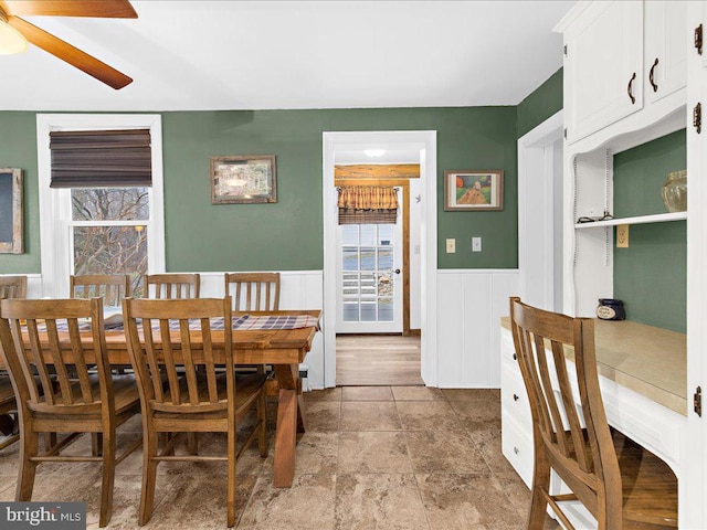 dining room with a ceiling fan and wainscoting