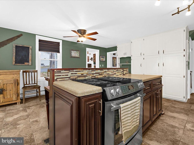 kitchen with a ceiling fan, a baseboard radiator, light countertops, electric stove, and white cabinetry