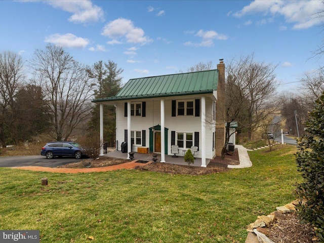 neoclassical home with metal roof, a porch, a front yard, and a standing seam roof