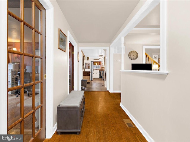 corridor with dark wood-style floors, visible vents, and baseboards