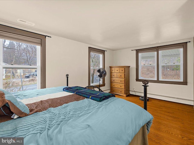 bedroom featuring a baseboard radiator, visible vents, and wood finished floors