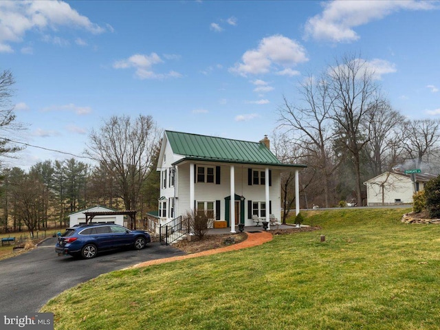 greek revival inspired property with a front lawn, a standing seam roof, a porch, metal roof, and a chimney