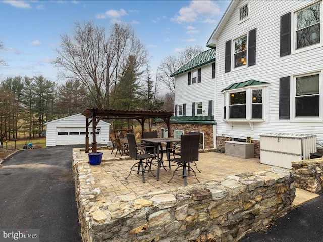 view of patio / terrace with outdoor dining space, an outbuilding, a garage, and a pergola