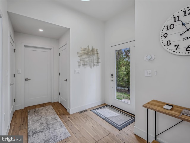 doorway to outside featuring wood finished floors, visible vents, and baseboards