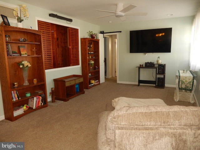 carpeted living room featuring a barn door, a ceiling fan, and baseboards