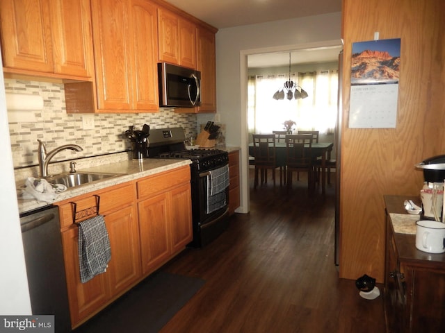 kitchen with a sink, backsplash, dark wood finished floors, stainless steel appliances, and light stone countertops