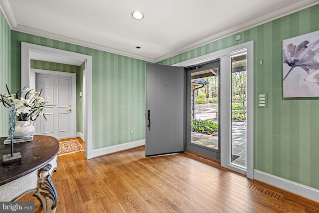 foyer entrance with wallpapered walls, visible vents, crown molding, baseboards, and light wood-style flooring
