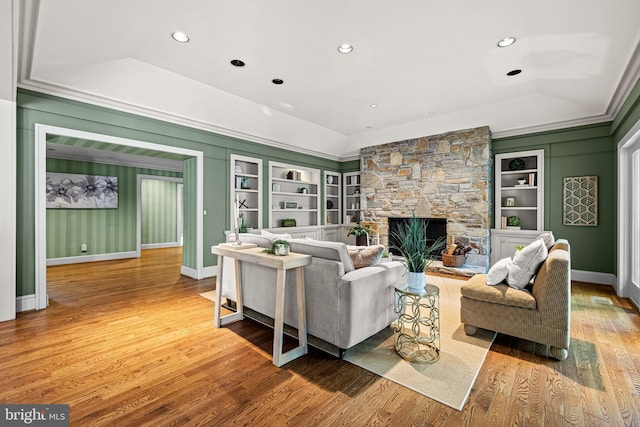 living area featuring baseboards, built in features, wood finished floors, and a fireplace
