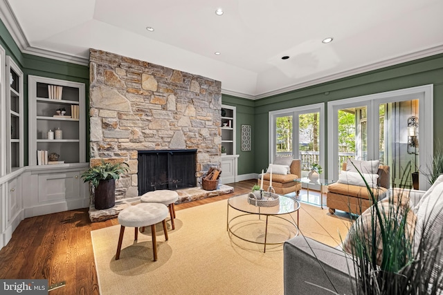 living area featuring recessed lighting, wood finished floors, built in shelves, and a stone fireplace