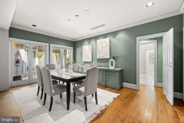 dining space with light wood finished floors, visible vents, crown molding, and french doors