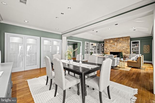 dining space with built in shelves, ornamental molding, french doors, and light wood-style flooring