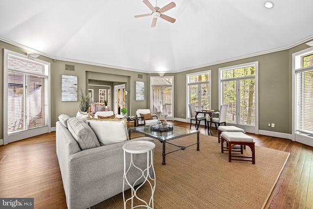 living area with vaulted ceiling, hardwood / wood-style flooring, ceiling fan, baseboards, and ornamental molding