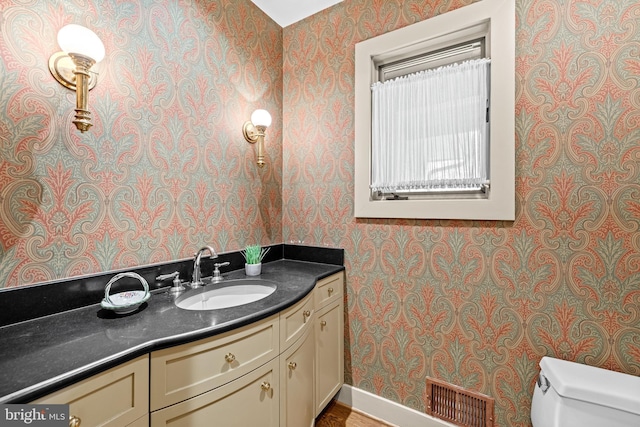 bathroom featuring wallpapered walls, visible vents, toilet, and vanity