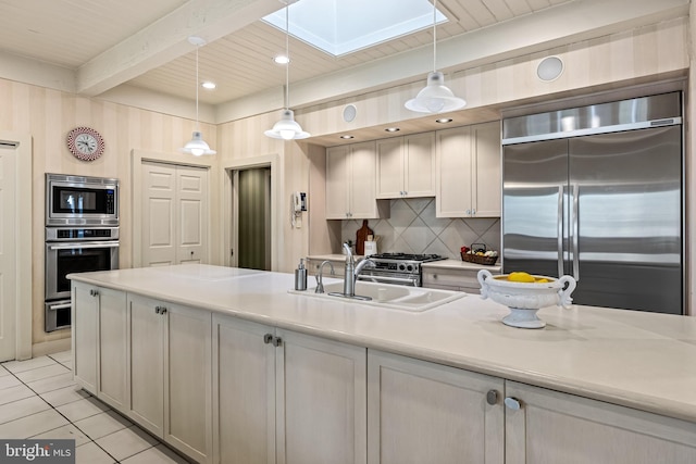 kitchen featuring a sink, backsplash, a skylight, built in appliances, and beamed ceiling