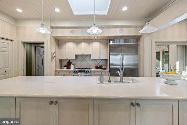 kitchen with recessed lighting, premium appliances, light countertops, a sink, and decorative backsplash
