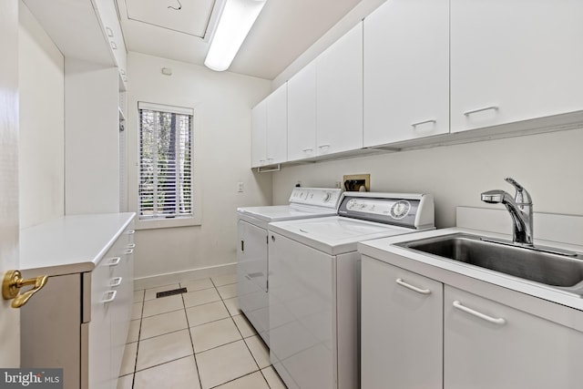 laundry room with a sink, light tile patterned floors, cabinet space, baseboards, and independent washer and dryer