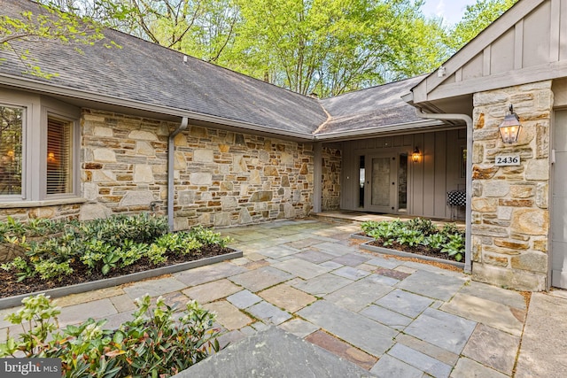 property entrance featuring stone siding, board and batten siding, and a shingled roof