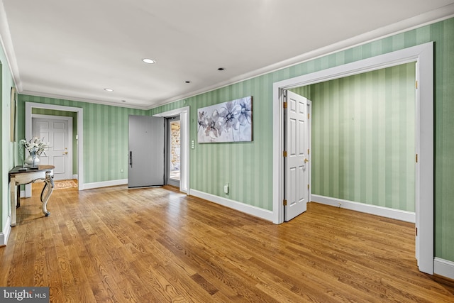 foyer featuring baseboards, crown molding, and wood finished floors
