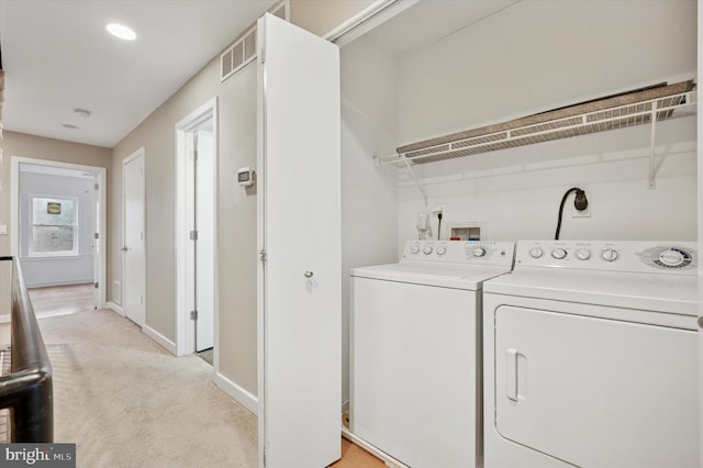 washroom with washing machine and clothes dryer, visible vents, baseboards, light carpet, and laundry area