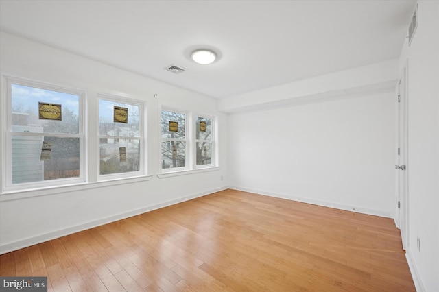 empty room featuring visible vents, baseboards, and light wood-type flooring